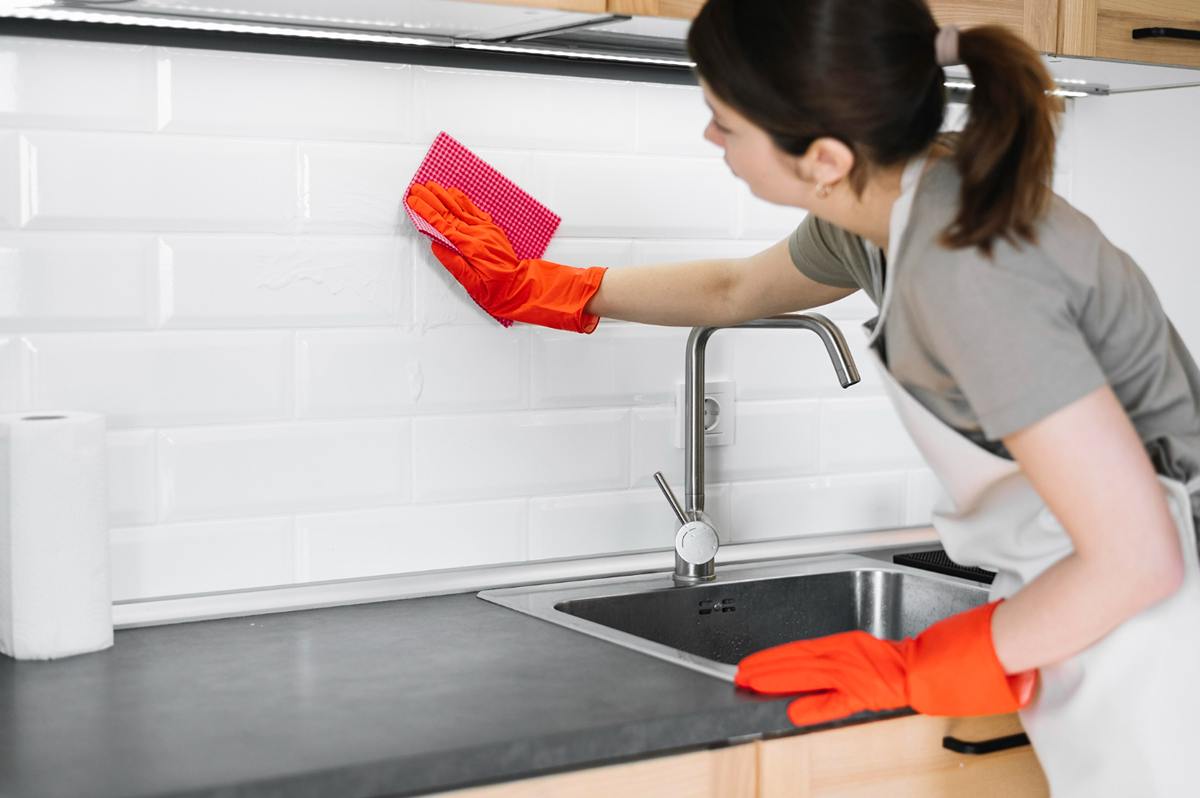 Cleaning supplies for granite composite kitchen sink, including dish soap, baking soda, and a soft sponge